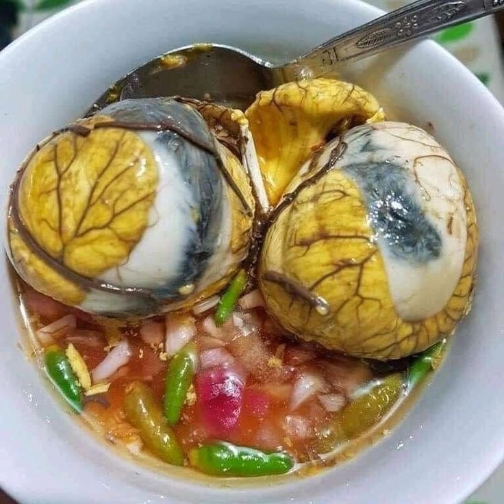 a white bowl filled with food on top of a table next to a person holding a spoon