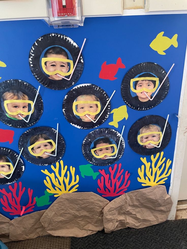 a bulletin board with pictures of children's faces and corals on the wall