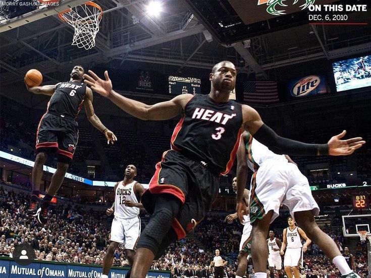 a basketball player jumping up to dunk the ball in front of other players on the court