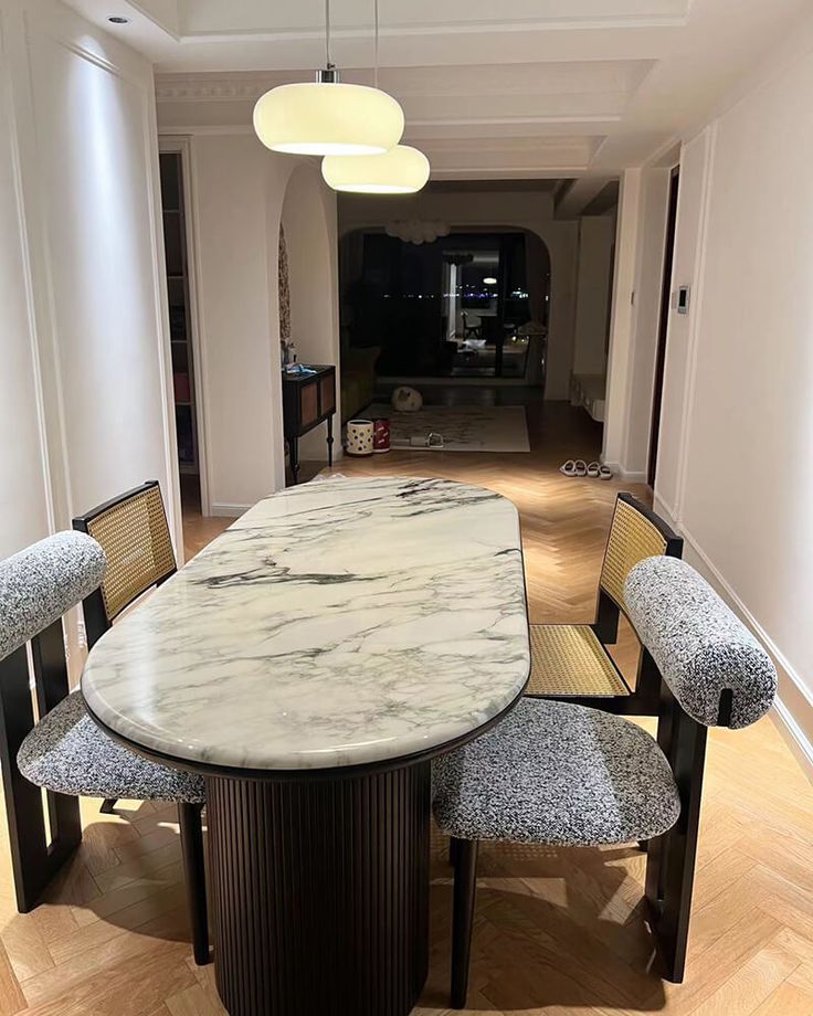 a dining table with four chairs and a marble top in the middle of a room