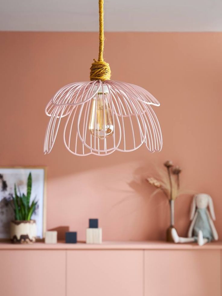 a white light hanging from a ceiling in a living room with pink walls and furniture