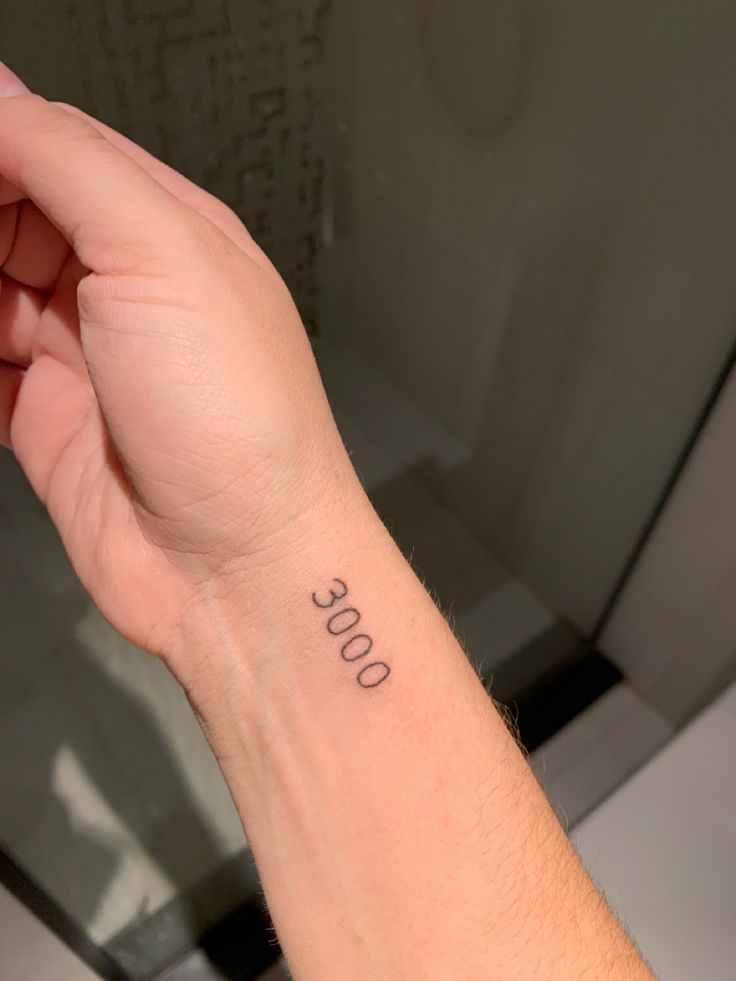 a person with a small tattoo on their left wrist and the word boo written in black ink