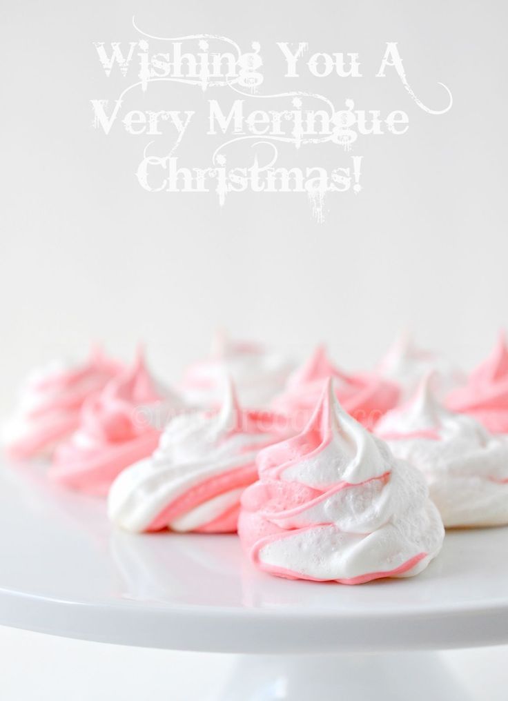 pink and white meringue cookies sitting on top of a cake plate with the words wishing you a very meringue christmas