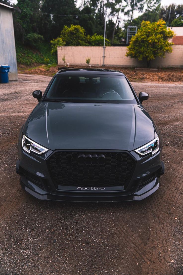 the front end of a black car parked in a parking lot