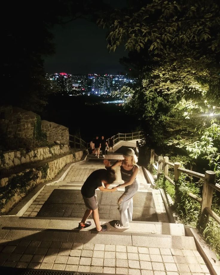 two men are standing on the stairs in front of a cityscape at night