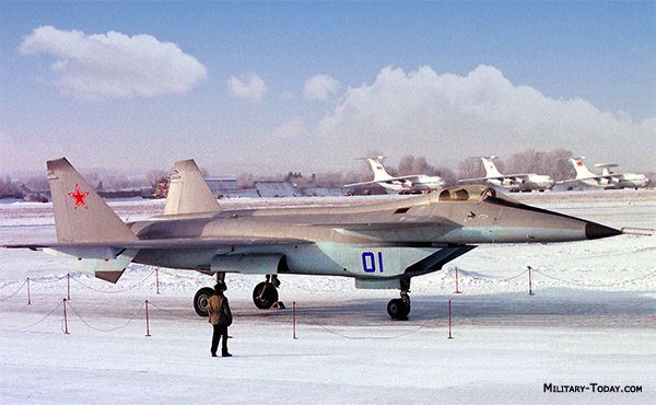 a fighter jet sitting on top of an airport tarmac next to other planes in the snow