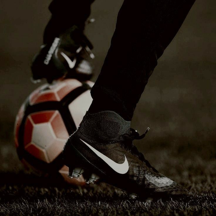 a soccer ball sitting on the ground next to a person's foot wearing black and white shoes