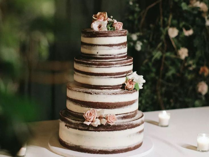 a three tiered wedding cake with flowers on the top and bottom is sitting on a table