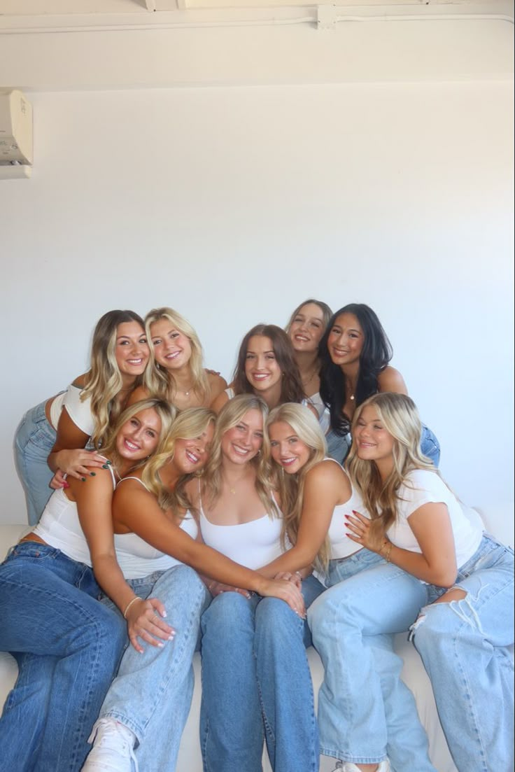 a group of young women sitting next to each other on top of a white couch