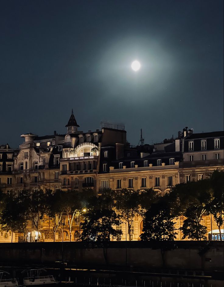 the full moon shines brightly over an old city at night