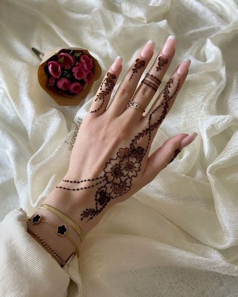 a woman's hand with henna on it next to a bowl of flowers