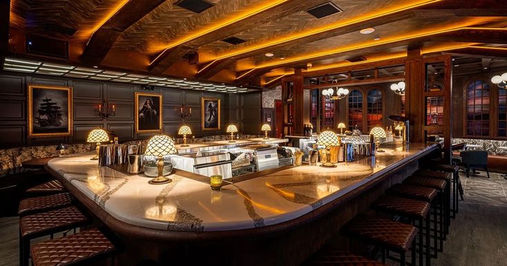 a large bar with lots of stools and lights on the counter top in a restaurant