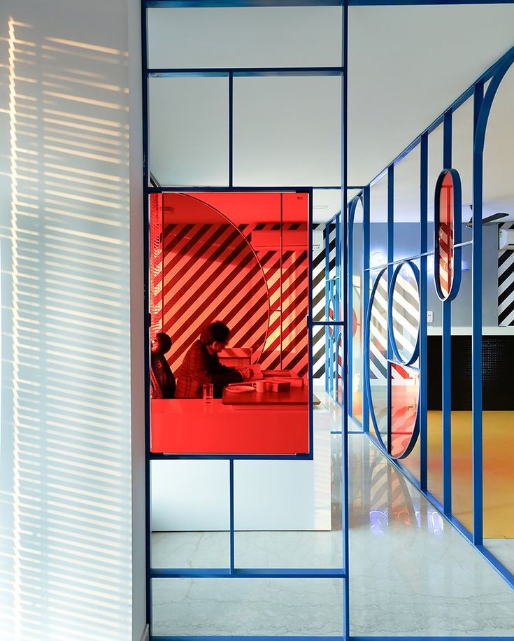 a person sitting at a table in front of a red and blue wall with circles on it