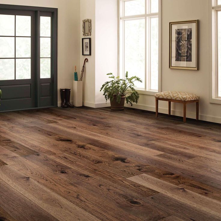 a living room with hardwood floors and white walls, potted plants on the floor