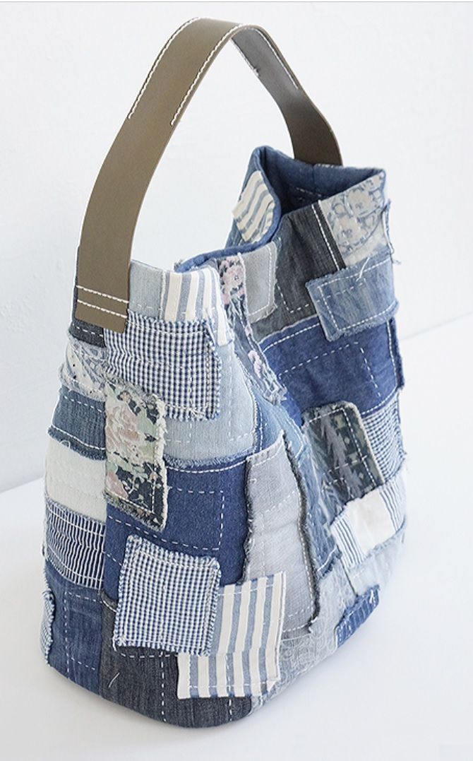 a bag made out of old jeans with leather handles and patchwork on the inside