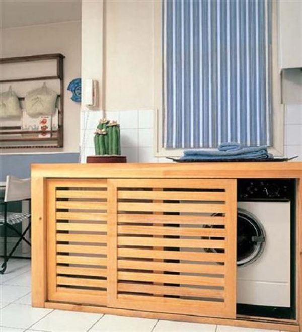 a wooden cabinet sitting in the middle of a room next to a window and a washing machine