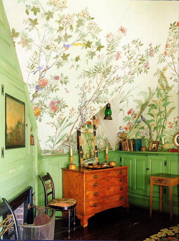 a room with green walls and floral wallpaper, including a dresser in the corner