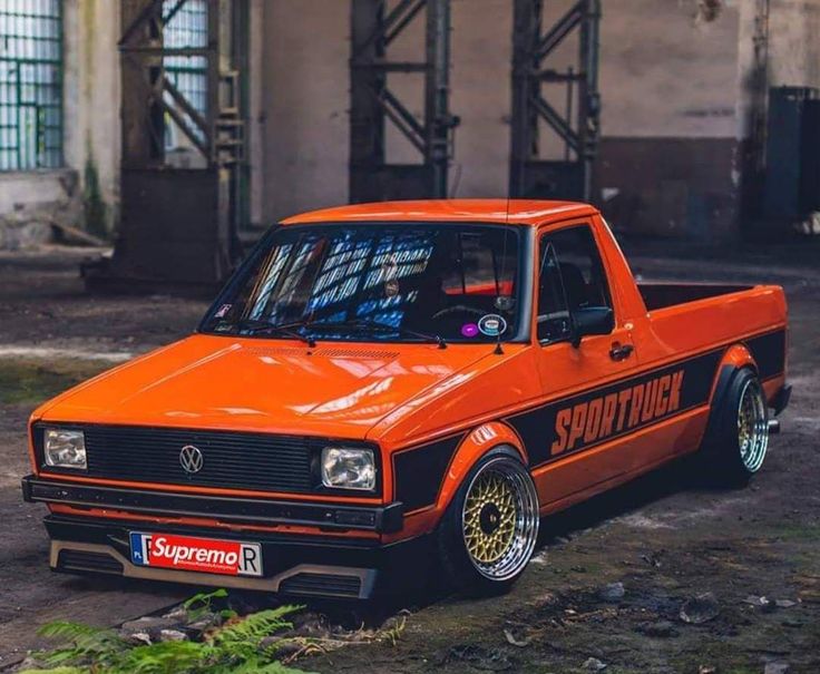 an orange pick up truck parked in front of a building