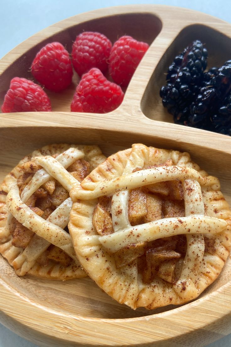 some raspberries and other fruit are on a wooden platter with two serving trays