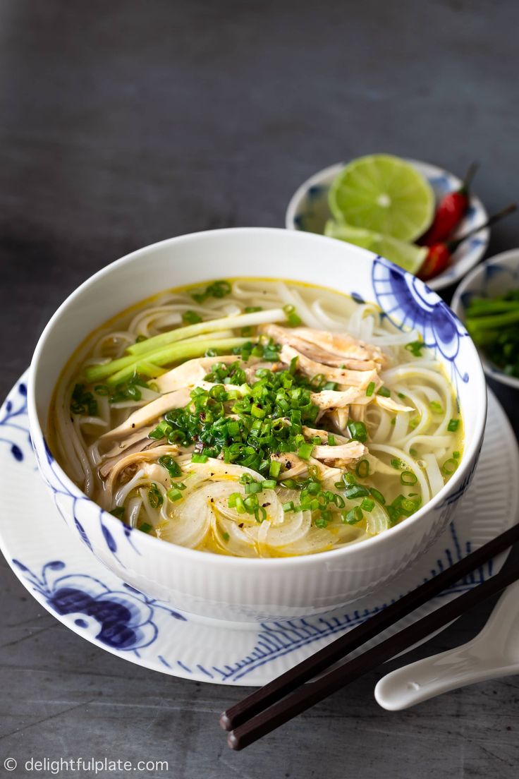 a bowl of chicken noodle soup with chopsticks next to it on a table