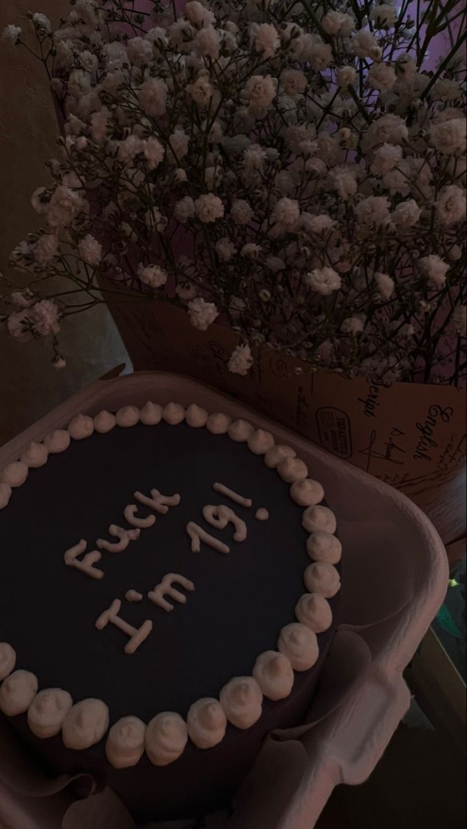 a birthday cake sitting on top of a table next to a vase filled with flowers