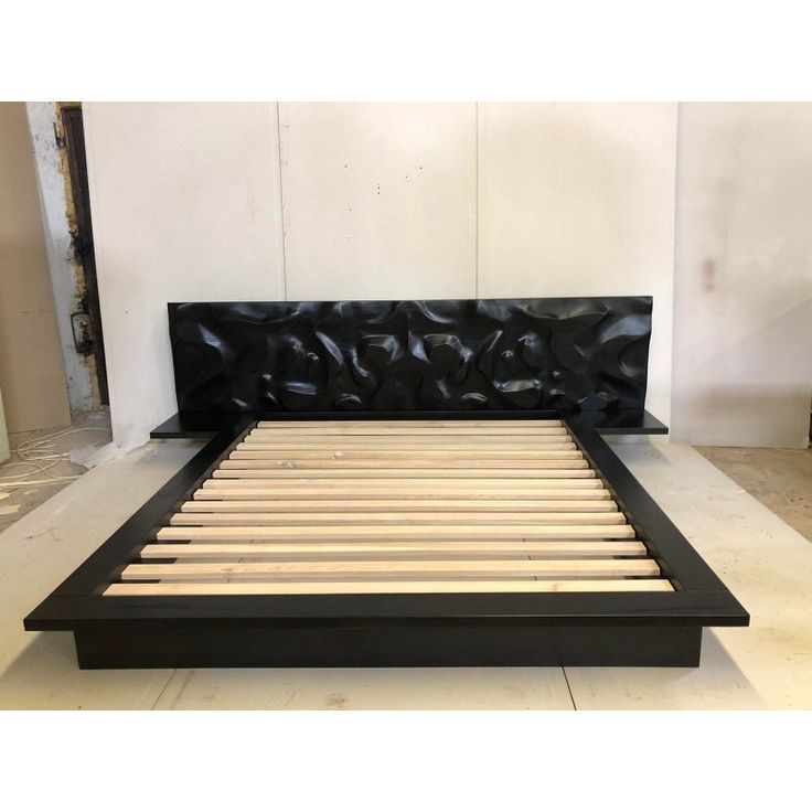 a bed with wooden slats and black leather headboard