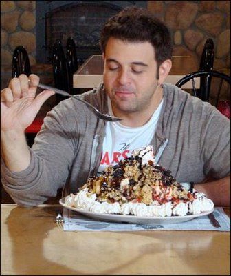 a man sitting at a table with a plate of food in front of his face