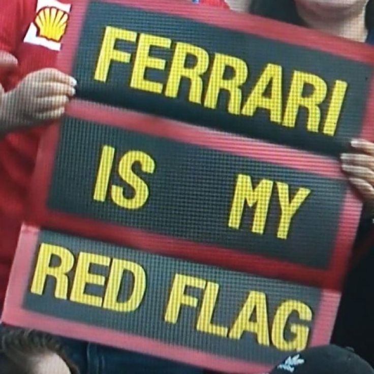 two people holding up signs that say ferrari is my red flag and ferrari is my