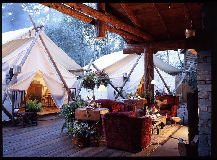 a group of tents set up on top of a wooden deck with chairs and tables