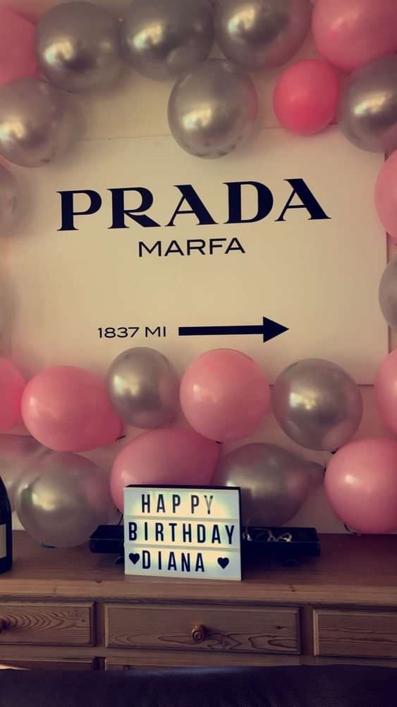 a birthday party with balloons and bottles on a table in front of a sign that says prada marfa