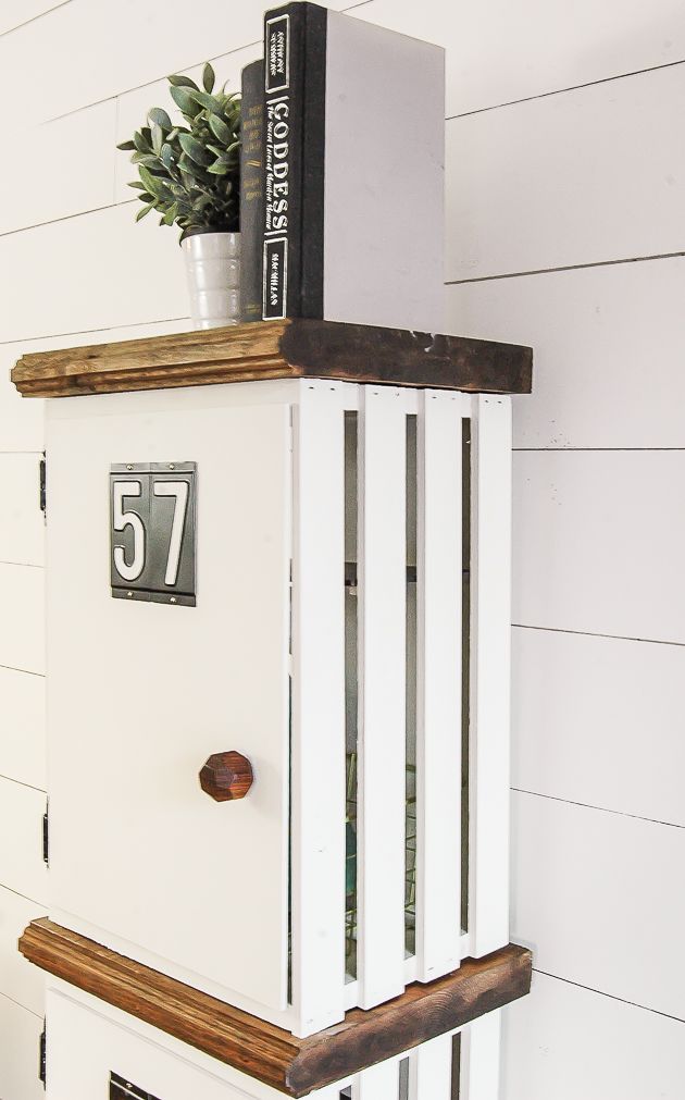 a white cabinet with a plant on top and a book shelf above it that has a clock