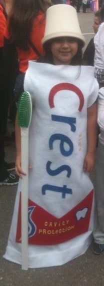 a young child wearing a costume made to look like a crayon bag and holding a toothbrush