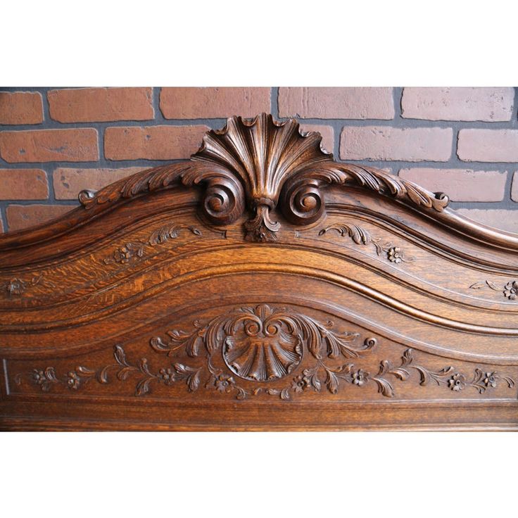 an ornate wooden bed frame against a brick wall