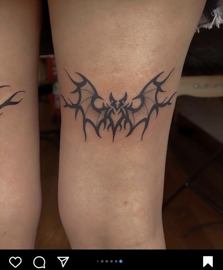 two legs with tattoos on them and one has a bat tattoo on it's leg