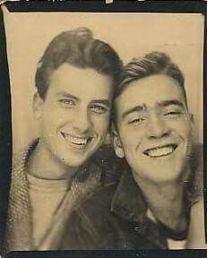 an old photo of two men smiling for the camera with one man's face to his chest