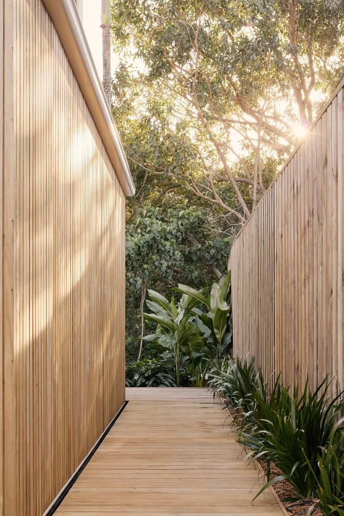 a wooden walkway between two buildings with trees in the background