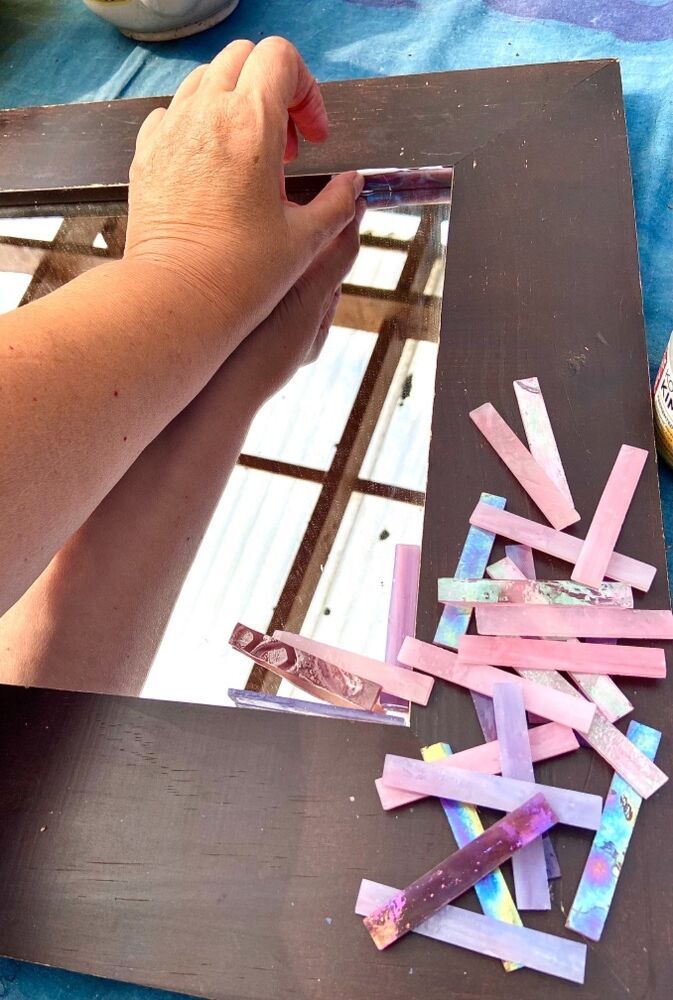 a person is making art with colored strips of tape on a table next to a mirror