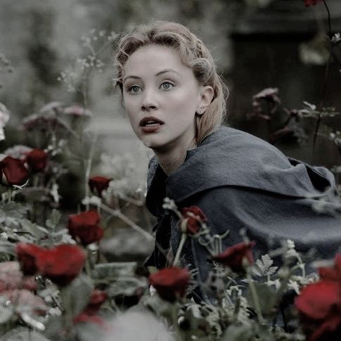 a woman is surrounded by flowers and looking at the camera