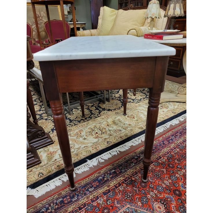 an antique table with marble top in the middle of a carpeted flooring area