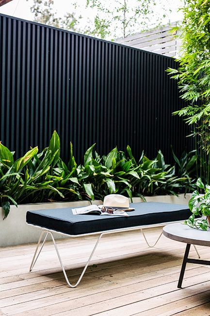 a table with a hat and sunglasses on it sitting next to some potted plants