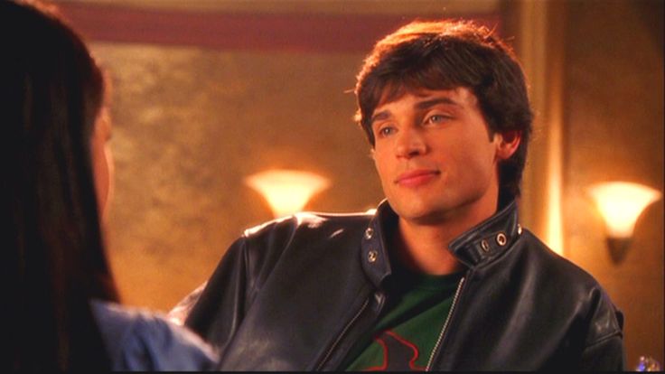 a young man in a leather jacket talking to a woman who is wearing a green shirt