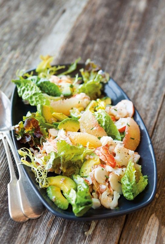 a salad with shrimp and lettuce on a blue plate next to a fork