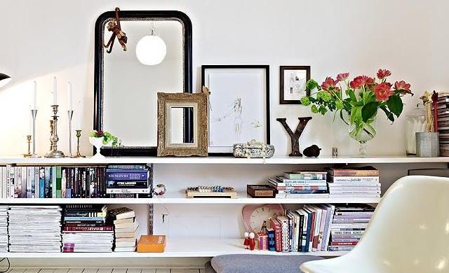 a living room filled with lots of furniture and books on top of a white shelf