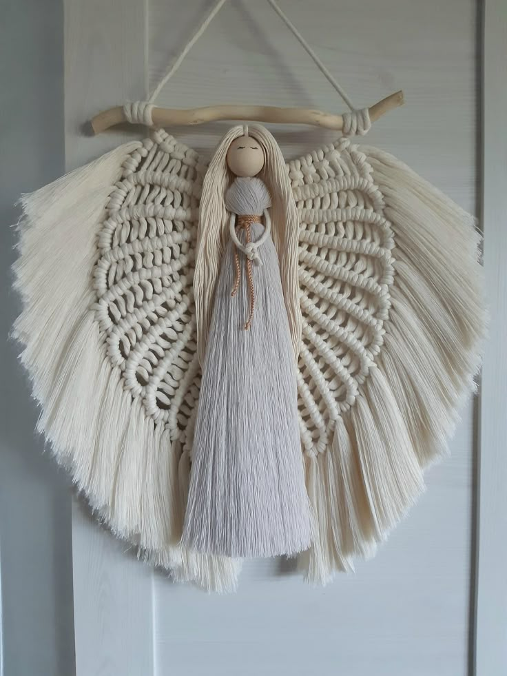 a white wall hanging with tassels and a doll