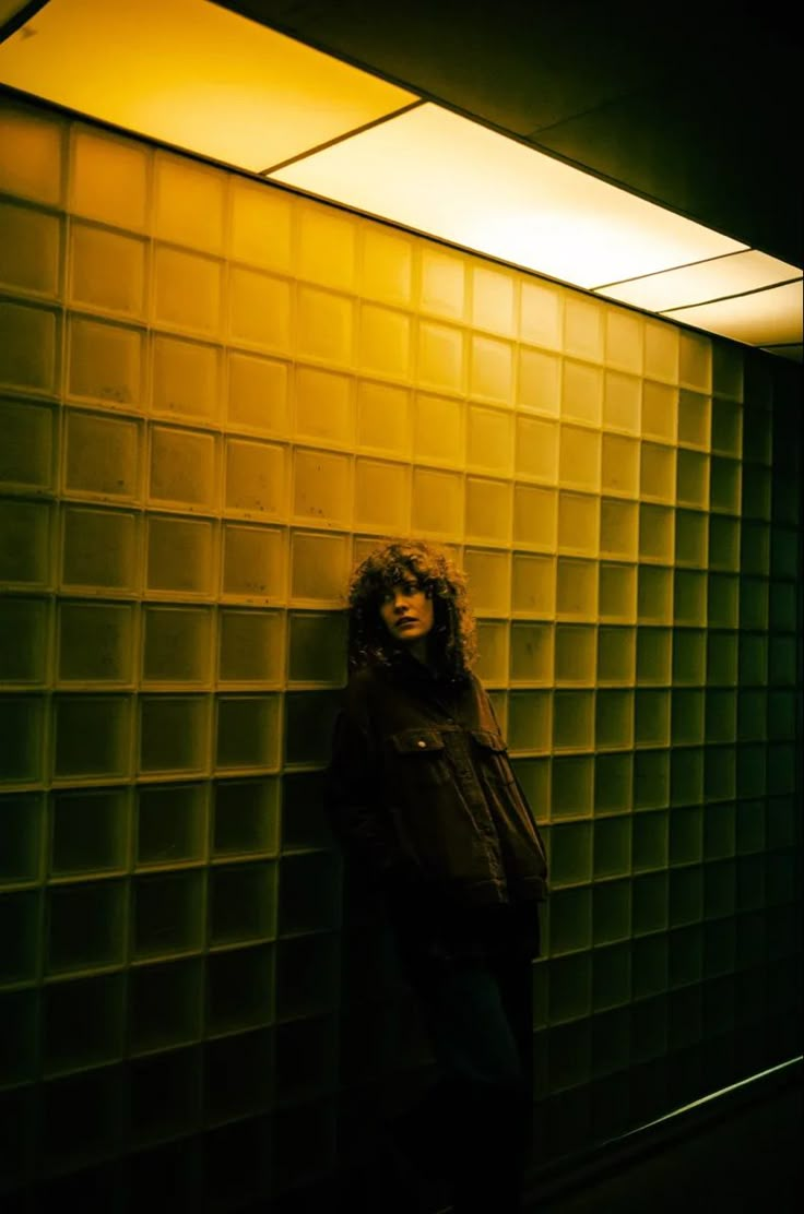 a woman standing in front of a glass block wall