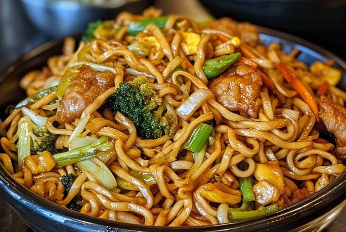 a bowl filled with noodles, meat and vegetables