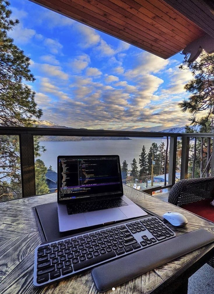 a laptop computer sitting on top of a wooden table next to a keyboard and mouse