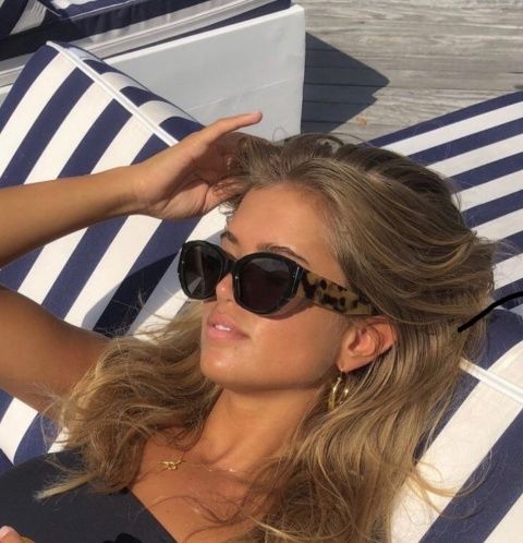 a beautiful woman laying on top of a blue and white striped beach chair