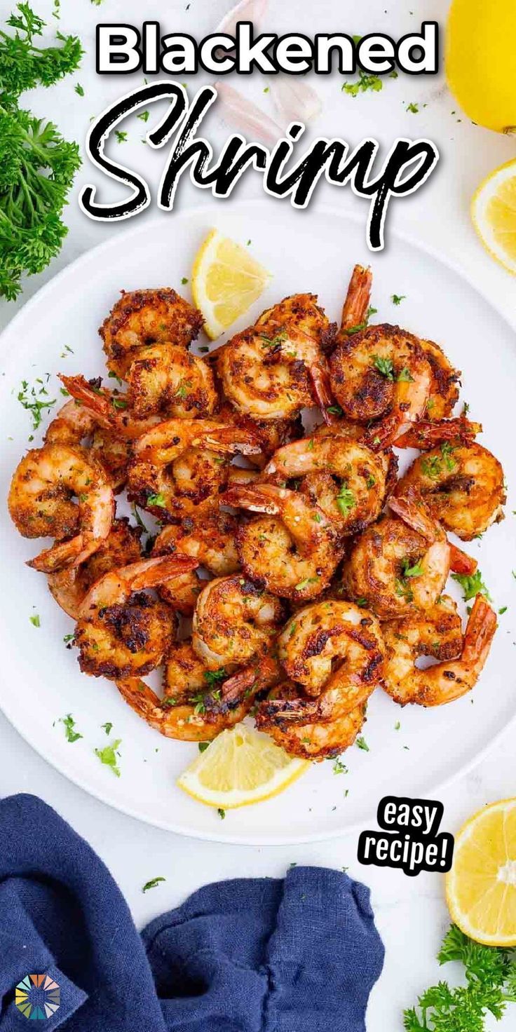 grilled shrimp on a white plate with lemon wedges and parsley garnish