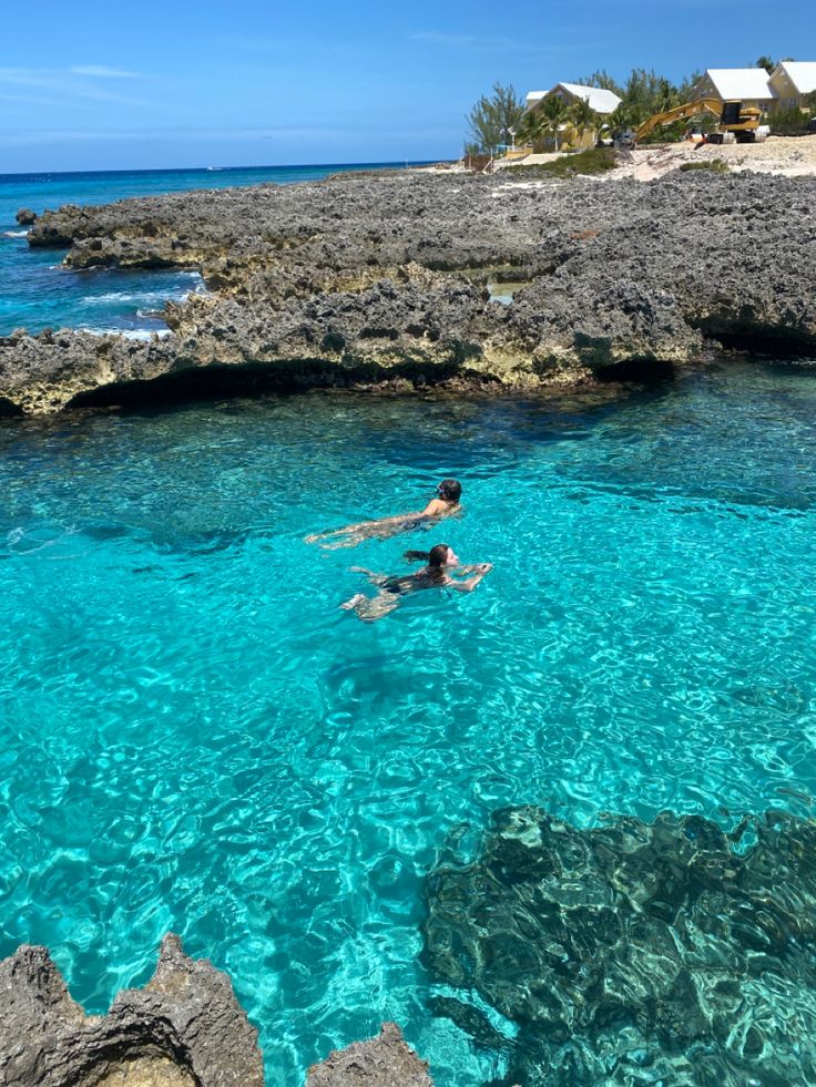 a person swimming in the ocean near some rocks